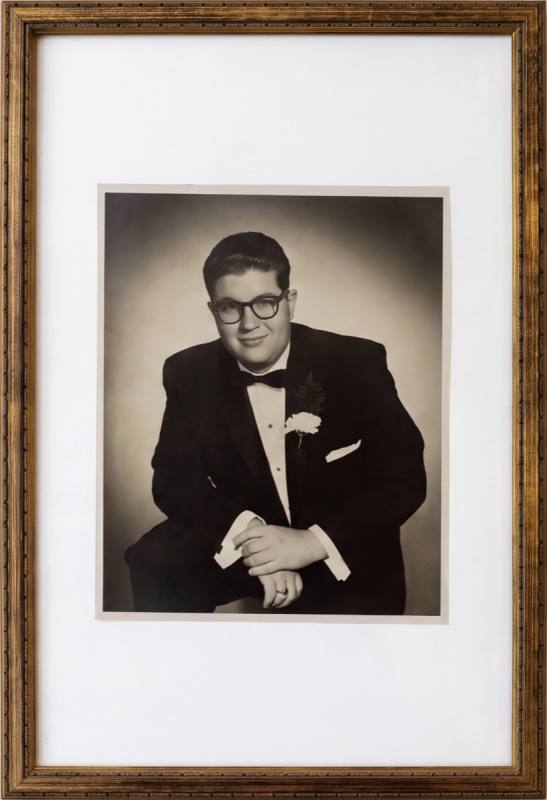 Framed studio portrait, a young man in a tuxedo with a carnation boutonniere